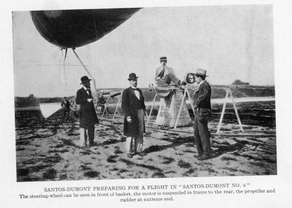 SANTOS-DUMONT PREPARING FOR A FLIGHT IN "SANTOS-DUMONT NO. 6"
The steering-wheel can be seen in front of basket, the motor is suspended in frame to the rear, the propeller and rudder at extreme end.